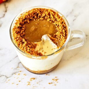 one serving of salted caramel biscoff cheesecake in a glass mug