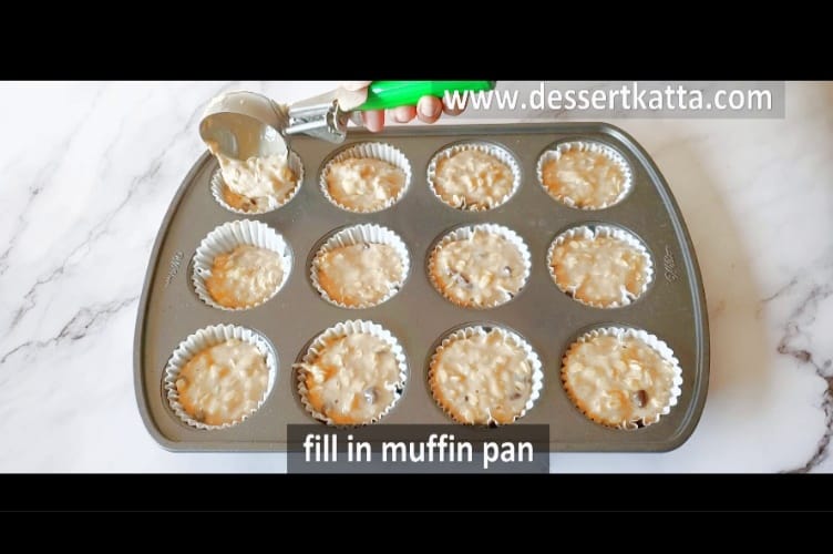 distributing muffin batter with green ice cream scoop in 12 cupcake liners