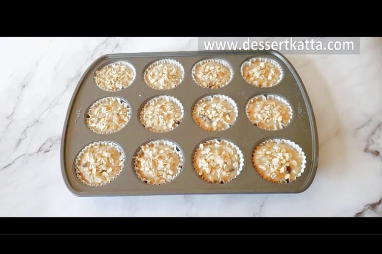 oats are added on top of muffin batter divided in cupcake pan