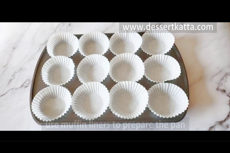 cupcake pan is lined up with 12 white cupcake liners.