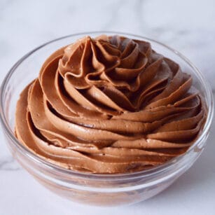 small glass bowl contains swirls of fudgy chocolate frosting