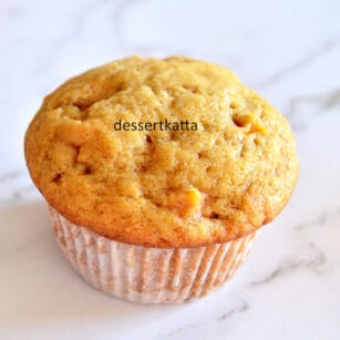 moist apple cinnamon muffin with cupcake liner placed on marble surface