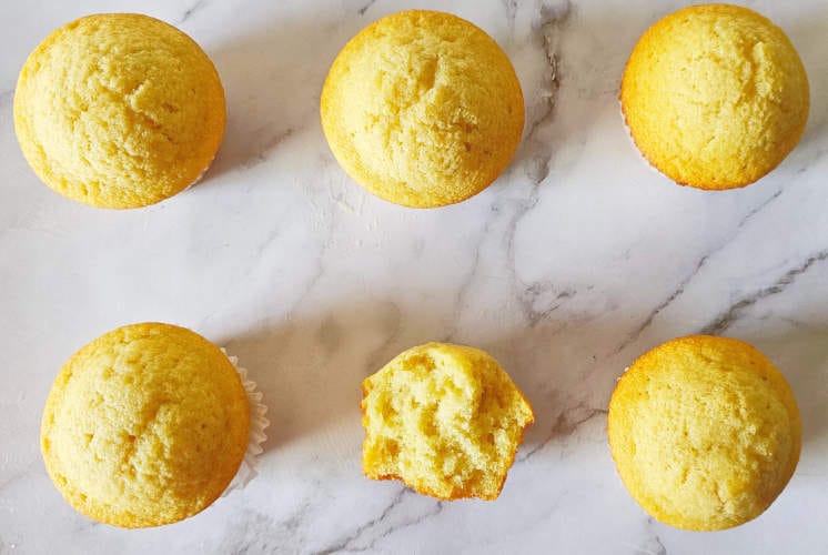 top shot of 6 vanilla muffins recipe with one muffin showing the texture from inside