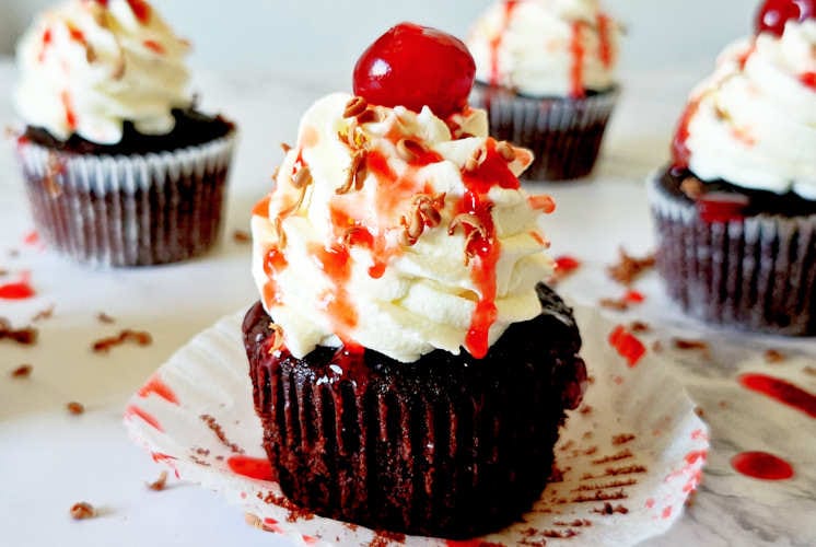 front shot of black forest cupcake with few cupcakes in the background