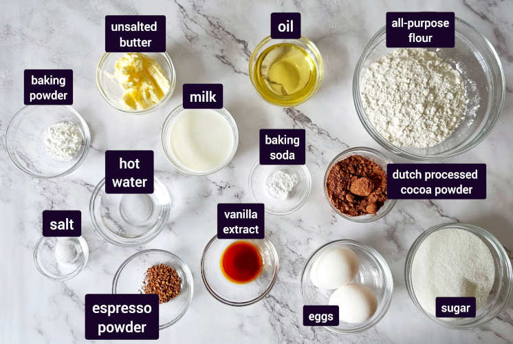ingredients for chocolate cake are placed on marble background in small bowls to prepare chocolate Nutella cake