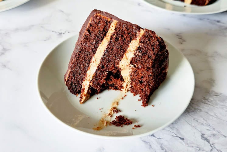 one piece of chocolate Nutella cake placed on white plate with one slice in the background placed on marble surface