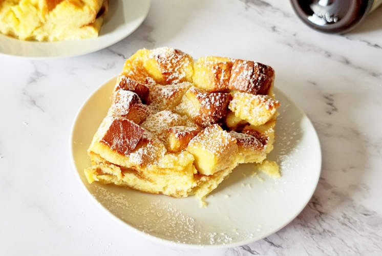 vanilla bread pudding served on a white plate and one more serving in the background