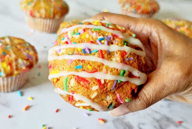 single funfetti muffins is held in one hand with few muffins in the background