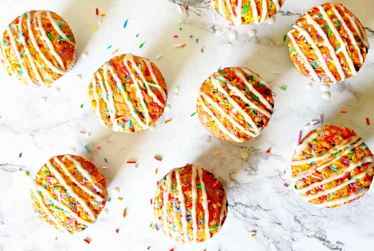 top shot of funfetti muffins garnished with vanilla glaze placed on marble surface